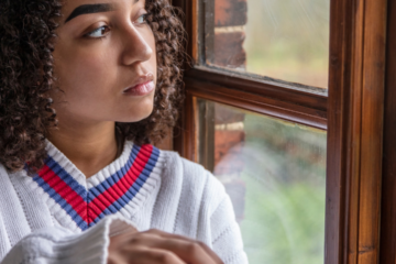 girl looking sadly out window showing social media's impact on teens